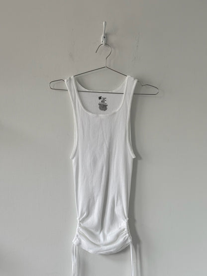 White tank top on a hanger against a plain wall