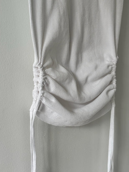 White ribbed tank top with a tie detail on a plain background