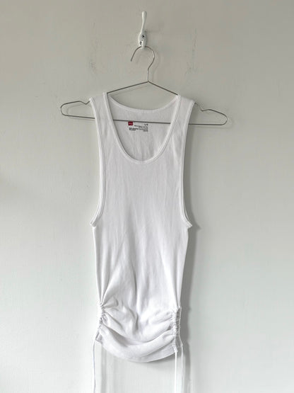White tank top hanging on a hanger against a plain white background