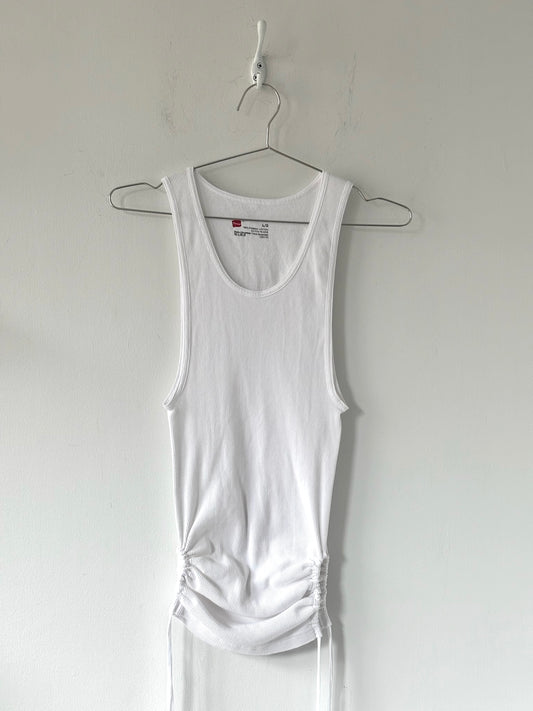 White tank top hanging on a hanger against a plain white background