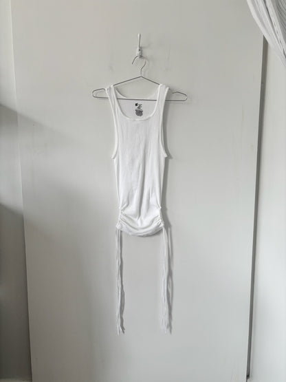 White tank top hanging on a hook against a white wall