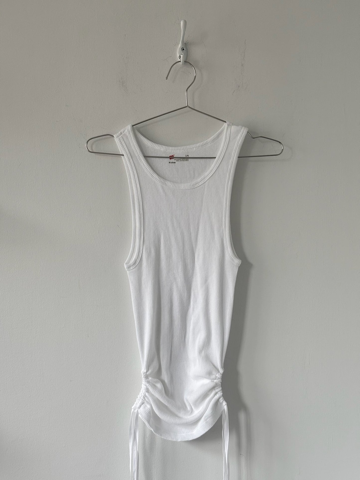 White tank top on a hanger against a plain background