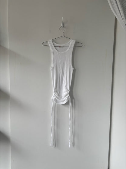 White tank top hanging on a hook against a plain wall