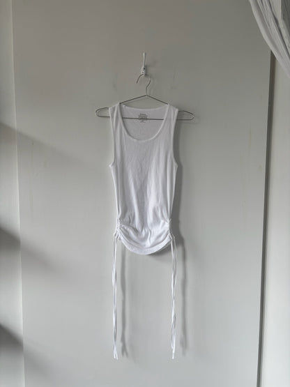White tank top with ties hanging on a hook against a plain wall.