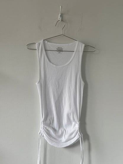 White tank top on a hanger against a plain wall